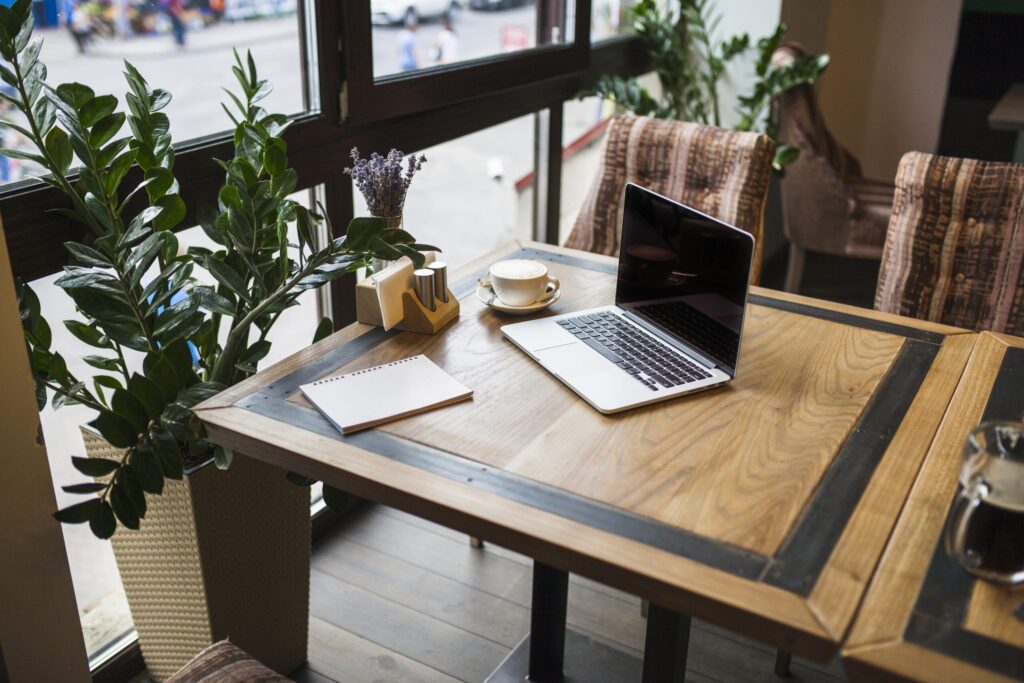 laptop with notepad cafe table scaled.jpg