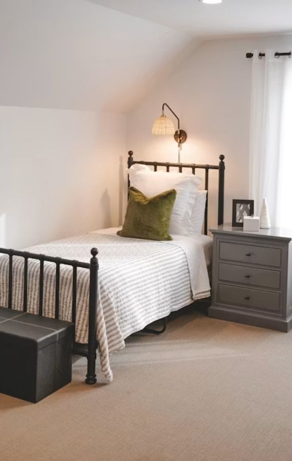 Hampshire holiday rental single bedroom with a black metal frame bed, striped bedding, and a grey nightstand.