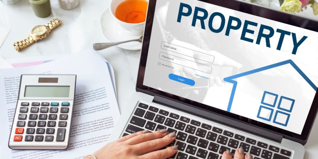 Laptop screen with the word 'PROPERTY' and a house icon, next to a calculator on a desk.